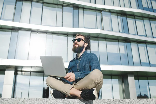 Businessman in sunglasses with laptop outdoors in front of offic — Stock Photo, Image
