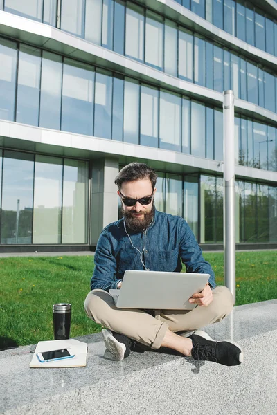 Hombre de negocios en gafas de sol con portátil al aire libre frente a offic — Foto de Stock