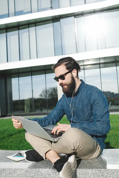 Hombre de negocios en gafas de sol con portátil al aire libre frente a offic —  Fotos de Stock