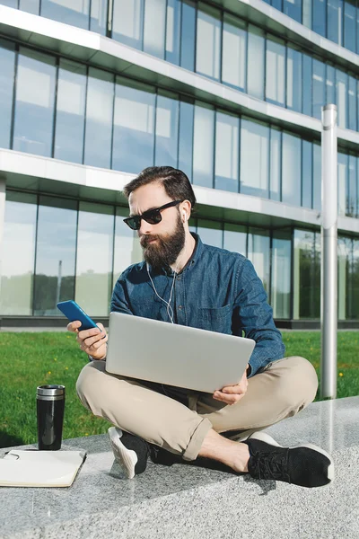 Empresário em óculos de sol com laptop fazendo chamada ao ar livre — Fotografia de Stock