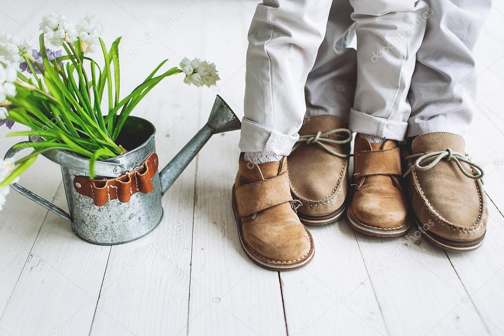 Legs of boy and man, in moccasins with flowers