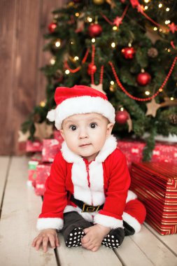 Xmas ağacı yakınındaki hediyeler ile Noel Baba kıyafetli bebek