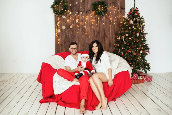 Hipster vader en moeder bedrijf baby in santa pak. — Stockfoto