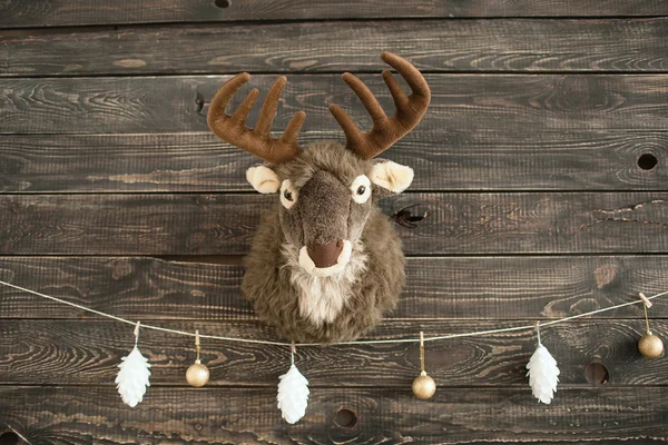 Plüschhirsch an einer Holzwand mit Weihnachtskugeln — Stockfoto