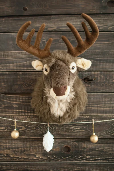 Plüschhirsch an einer Holzwand mit Weihnachtskugeln — Stockfoto