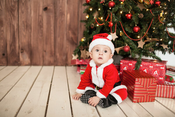 Dziecko w garnitur santa z darów w pobliżu drzewo xmas — Zdjęcie stockowe