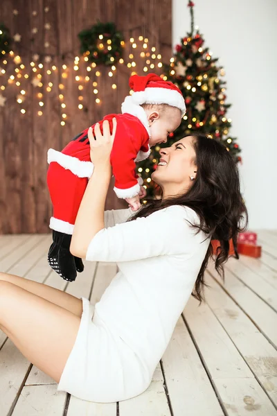 Jonge moeder bedrijf baby in santa pak. — Stockfoto