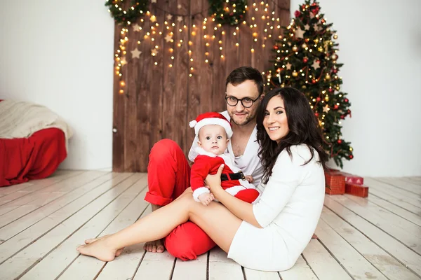 Hipster father and mother holding baby in santa suit — Stock Photo, Image