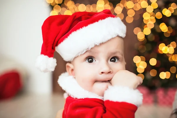 Söt baby i santa passar nära xmas tree — Stockfoto