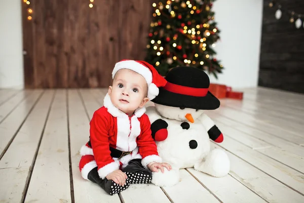 Bebê em terno de Papai Noel no chão perto da árvore de xmas — Fotografia de Stock