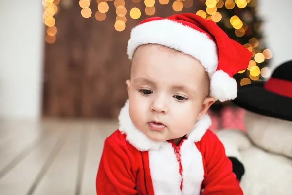 Dziecko w garnitur santa na podłodze w pobliżu drzewo xmas — Zdjęcie stockowe