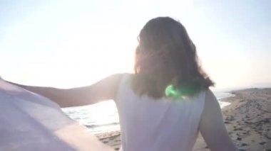 Tutan güzel kadın kumaş sahilde ışık ve güneşin batışını