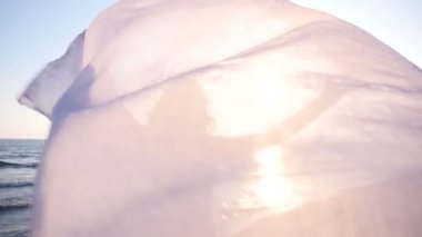 Tutan güzel kadın kumaş sahilde ışık ve güneşin batışını