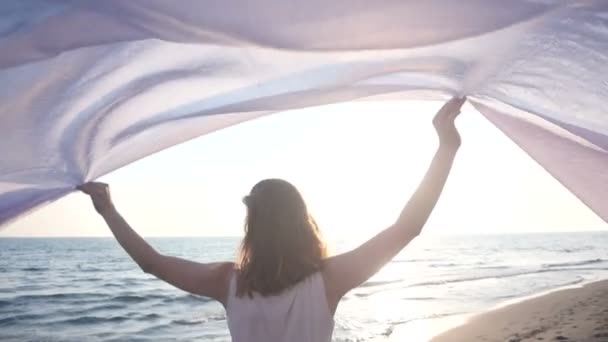 Όμορφη γυναίκα που κρατά ανοιχτό ύφασμα στην παραλία και να απολαύσετε το ηλιοβασίλεμα — Αρχείο Βίντεο