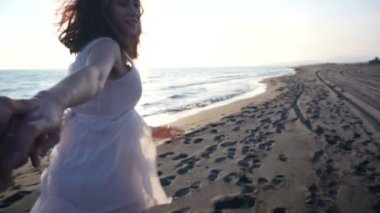 Genç çift günbatımı doğru yürüyen kadın önde gelen erkek arkadaş elele