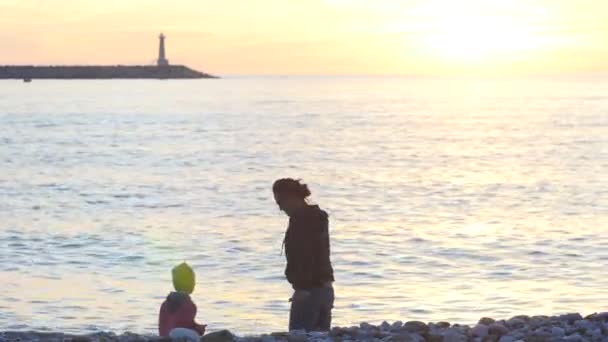 Madre e hijo lanzando guijarros al mar — Vídeo de stock