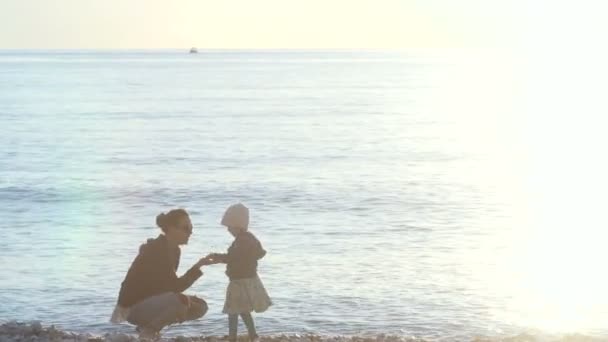 Madre e hijo lanzando guijarros al mar — Vídeos de Stock