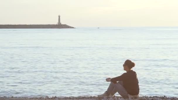 Una mujer sentada en la playa sola — Vídeos de Stock