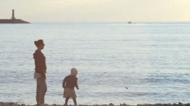 Anne ve çocuk denize taş atma
