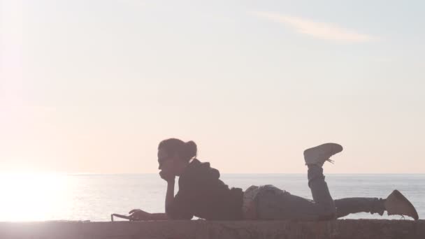 Nő használ egy tabletta a strandon során naplemente — Stock videók