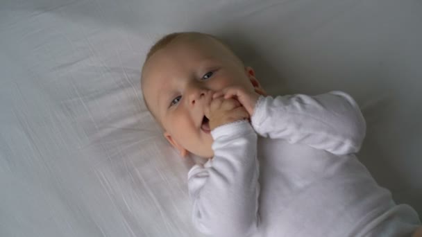 Madre hace cosquillas al bebé y él se ríe acostado en la cama — Vídeos de Stock