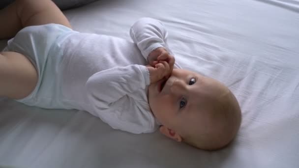 Moeder prikkelt de baby en hij lacht liggend op het bed — Stockvideo