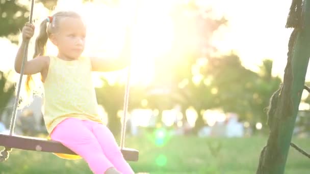 Menina bonita em um balanço no parque infantil — Vídeo de Stock