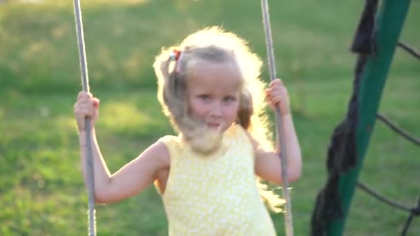 Mooi klein meisje op een schommel in de speeltuin — Stockvideo