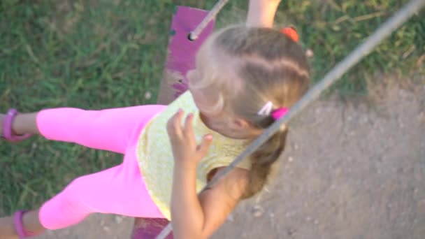 Menina bonita em um balanço no parque infantil — Vídeo de Stock