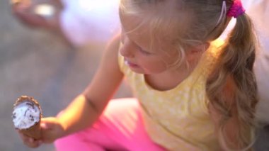 sevimli küçük kız anne kollarında Promenade otururken dondurma yemek