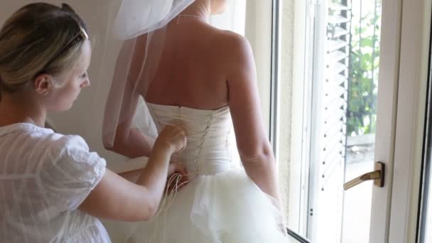 Dama de honor ayuda a la novia a usar un vestido — Vídeo de stock
