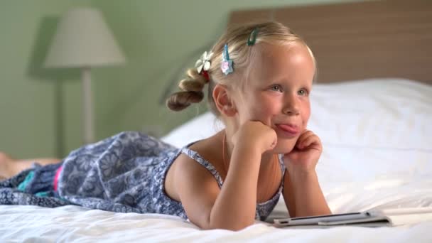 Pequena menina bonito joga um jogo no tablet — Vídeo de Stock