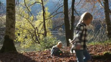 Mutlu Çocuklar Sonbahar Parkı 'nda oynuyor. Oğlan ve Kız Düşmüş Yaprak Atar ve Oynar.