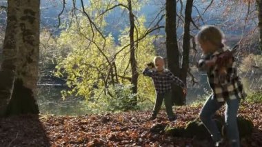 Mutlu Çocuklar Sonbahar Parkı 'nda oynuyor. Oğlan ve Kız Düşmüş Yaprak Atar ve Oynar.
