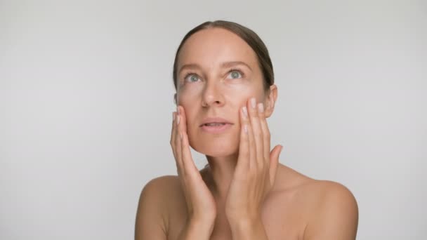 Close-up beauty portret van jonge vrouw met een gladde gezonde huid, ze zachtjes raakt haar gezicht met haar vingers op witte achtergrond — Stockvideo
