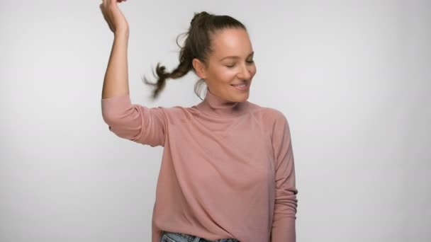 Mujer en una blusa rosa desata su cabello y sonríe — Vídeos de Stock