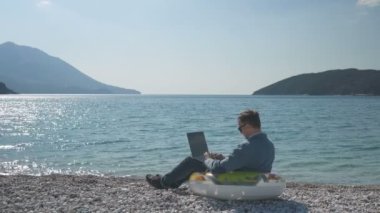 Kumsalda bilgisayarla çalışan serbest çalışan bir iş adamı.