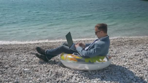 Freelancer hombre de negocios trabajando remotamente en el portátil en la playa — Vídeos de Stock