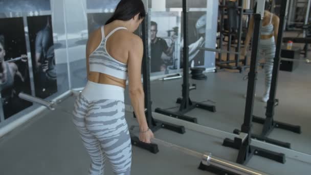 Primer plano de la mujer sexy en ropa deportiva haciendo barbell deadlifts mientras se ejercita en el gimnasio — Vídeos de Stock