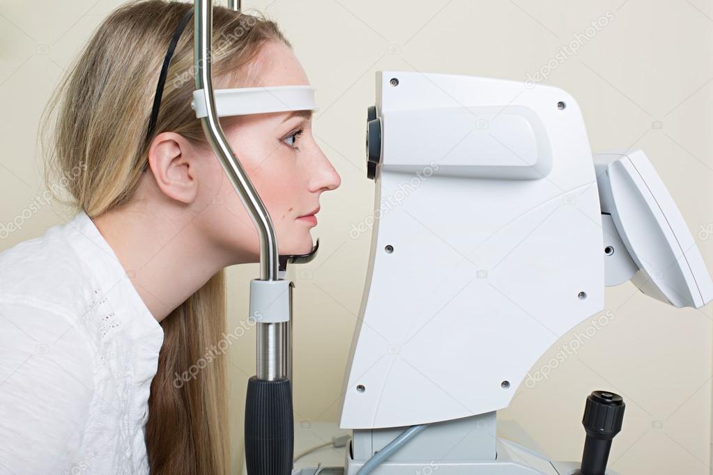 Young woman having her eyes examined by an eye handsome elderly doctor