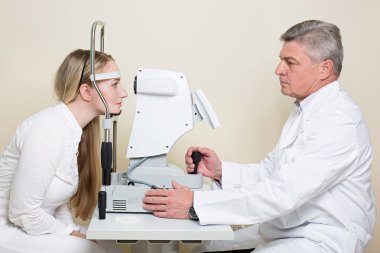 Genç kadın bir göz yakışıklı yaşlı doktor tarafından muayene gözlerini yaptırıyor