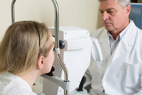 Jeune femme ayant les yeux examinés par un beau médecin âgé — Photo