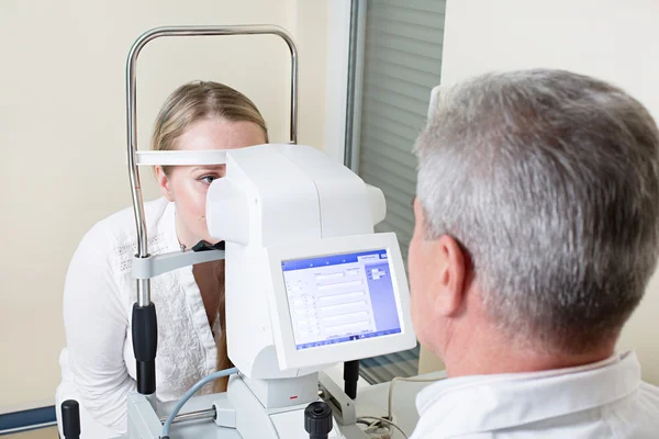 Jovem mulher ter seus olhos examinados por um olho bonito médico idoso — Fotografia de Stock