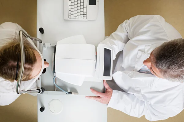 Mujer joven que tiene sus ojos examinados por un ojo guapo médico de edad avanzada — Foto de Stock