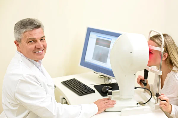 Mujer joven que tiene sus ojos examinados por un ojo guapo médico de edad avanzada — Foto de Stock