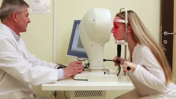 Young woman having her eyes examined by an eye handsome elderly doctor — Stock Video