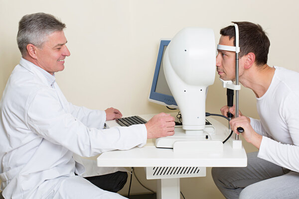 Man having his eyes examined by an eye elderly doctor.