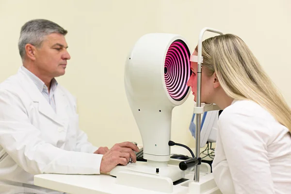 Jovem mulher ter seus olhos examinados por um olho bonito médico idoso . — Fotografia de Stock