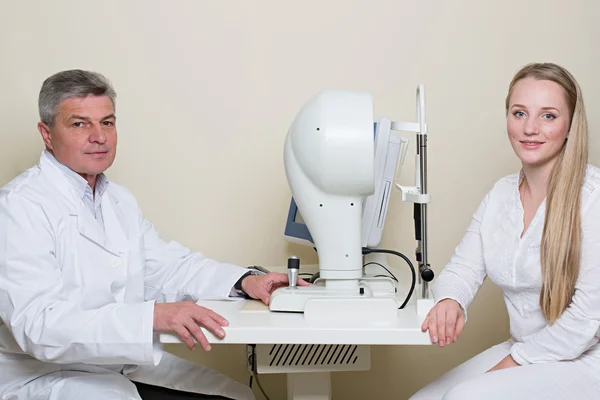 Mujer joven que tiene sus ojos examinados por un ojo guapo médico de edad avanzada . —  Fotos de Stock