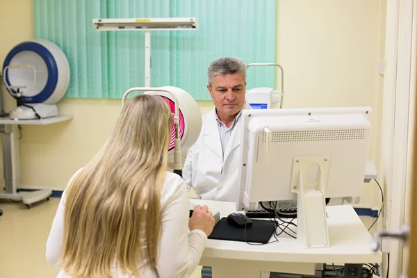 Jovem mulher ter seus olhos examinados por um olho bonito médico idoso . — Fotografia de Stock